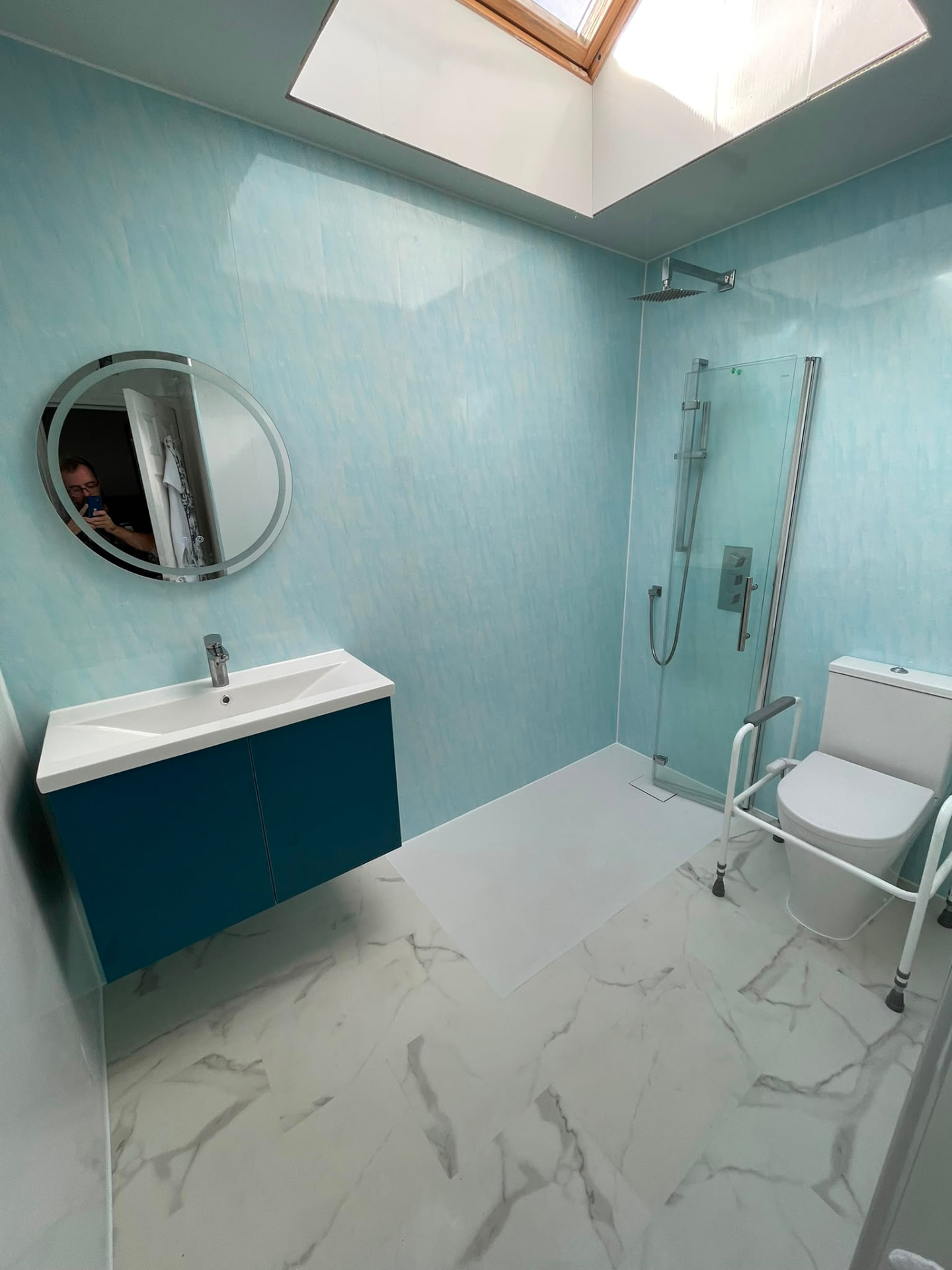 Finished accessible wet room with grab rails, shower seat and teal walls