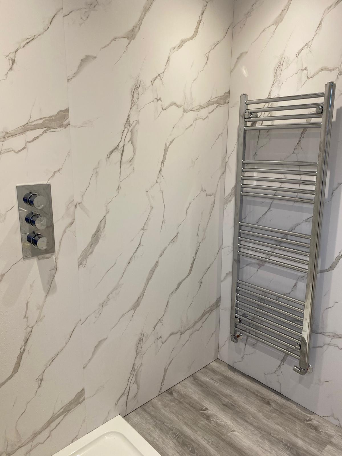 Chrome ladder towel rail and concealed thermostatic shower valve on marble effect panels