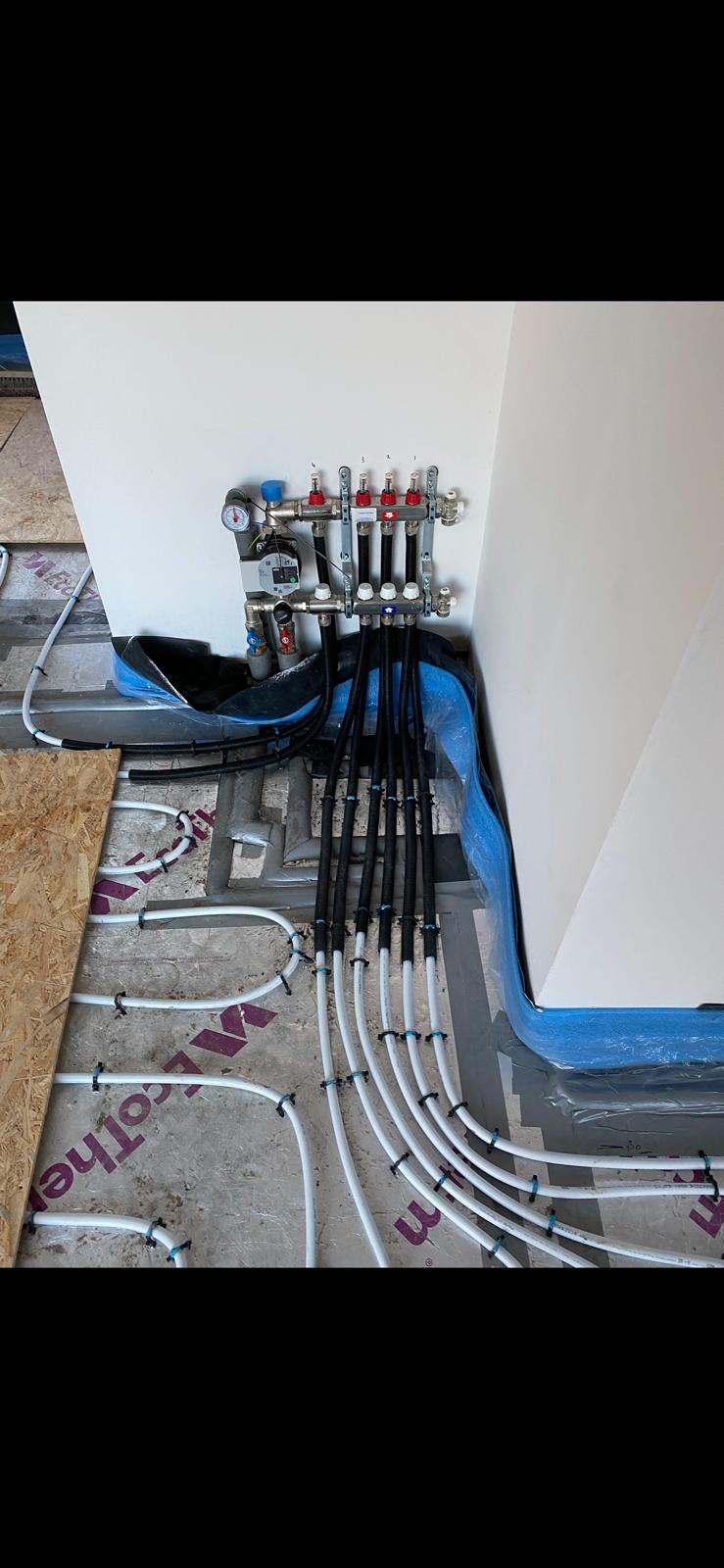 Underfloor heating manifold with flow meters, pump and zone valves connected to pipe loops