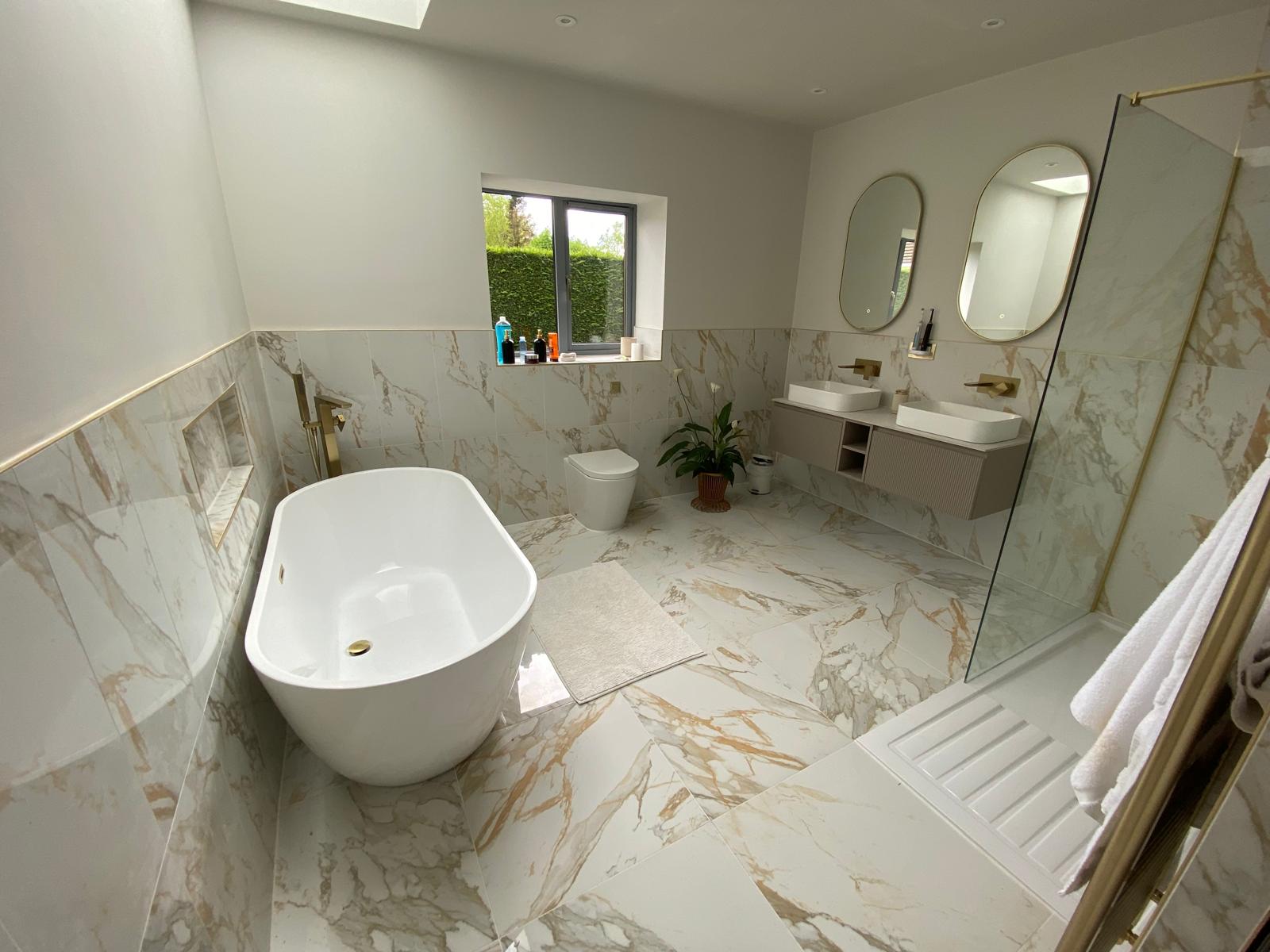 Marble effect bathroom with freestanding bath, twin oval mirrors and walk-in shower
