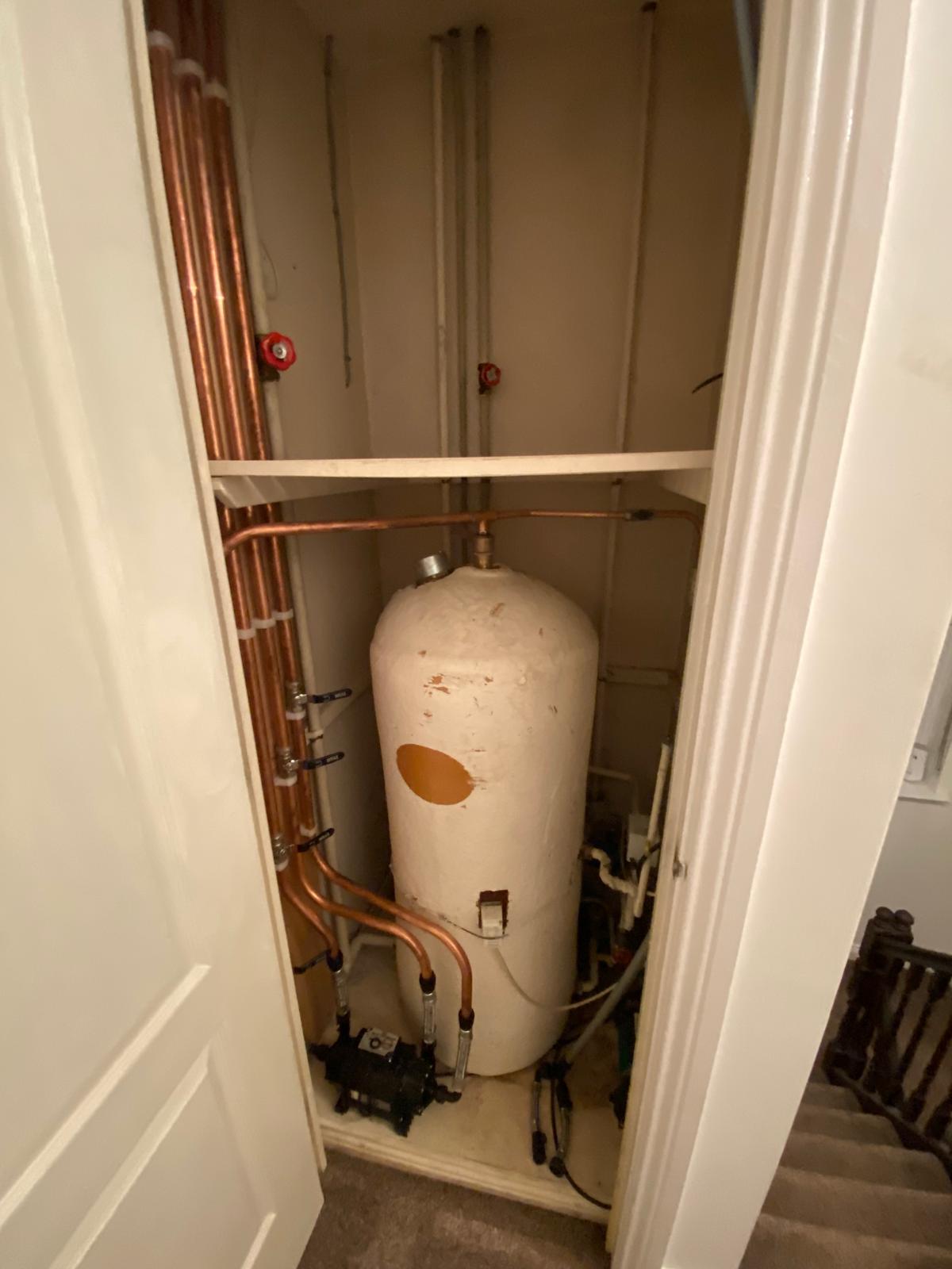 Twin shower pump fitted at the base of a hot water cylinder in an airing cupboard