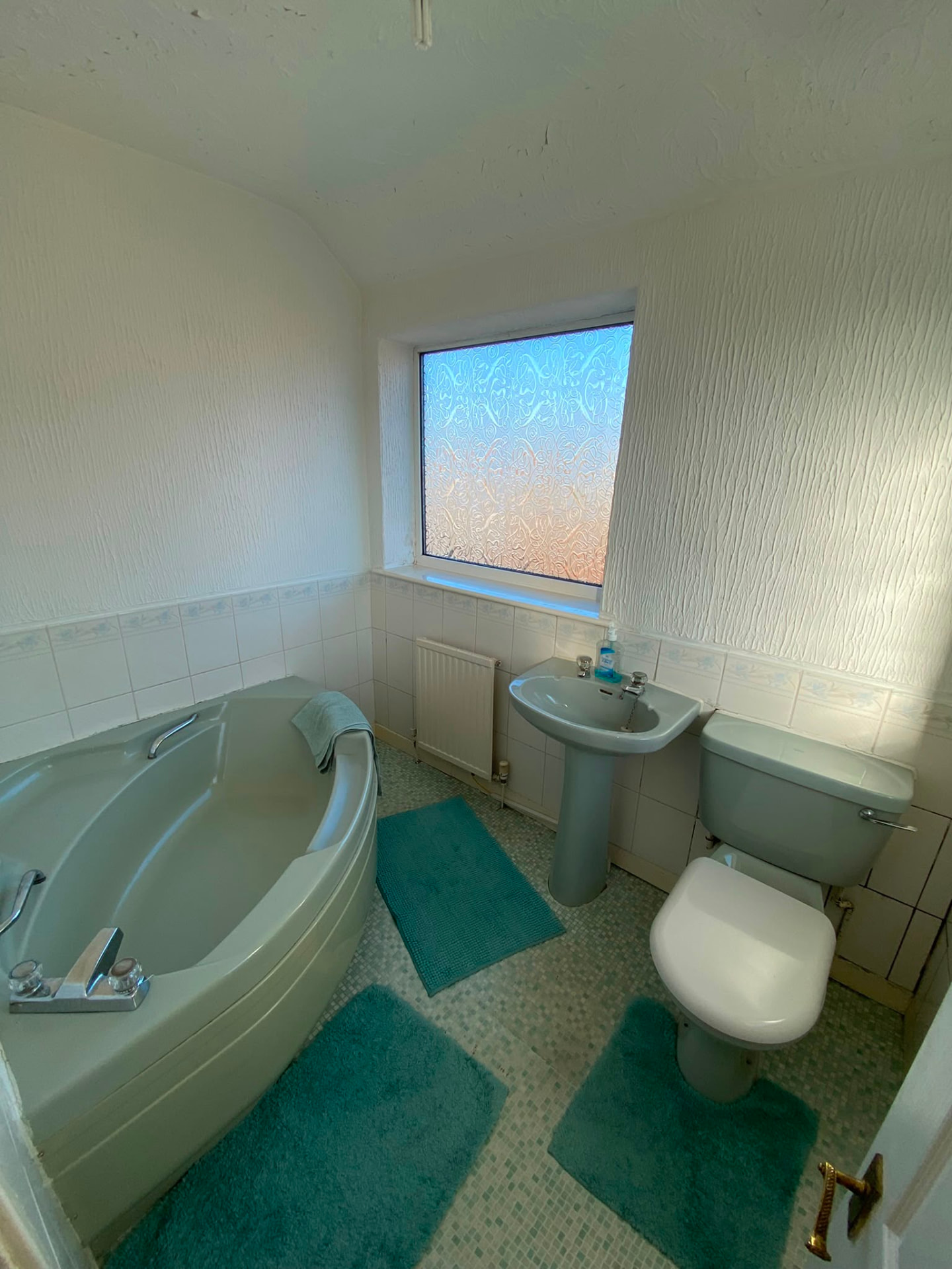 Original bathroom in Bedlington Station with green corner bath, pedestal basin and matching suite