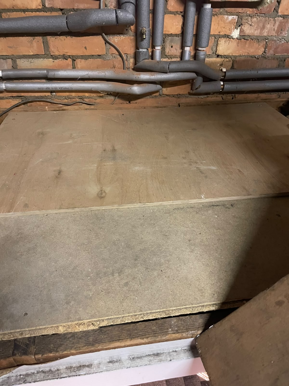 Plywood floor base installed beneath pipework in a loft for safe boiler working and maintenance