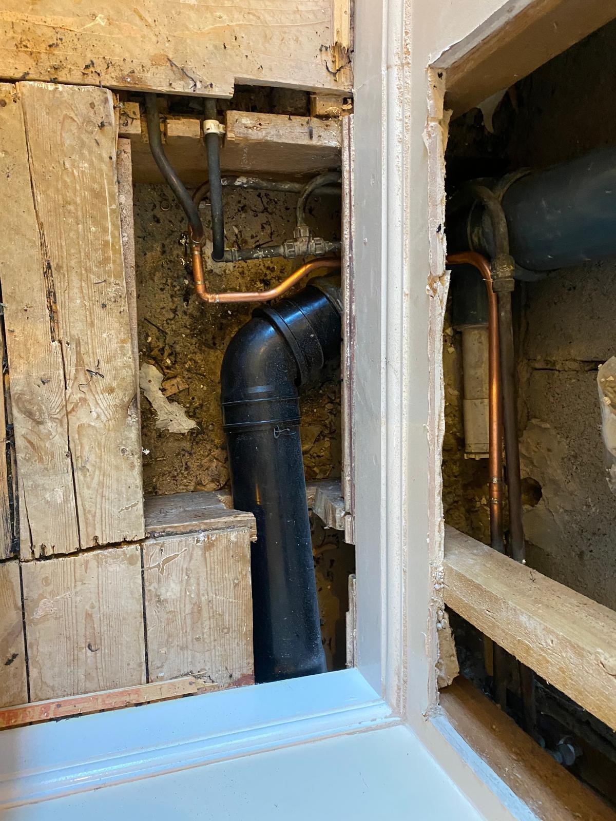 New black solvent weld waste pipe and clipped copper pipework in a tidy void