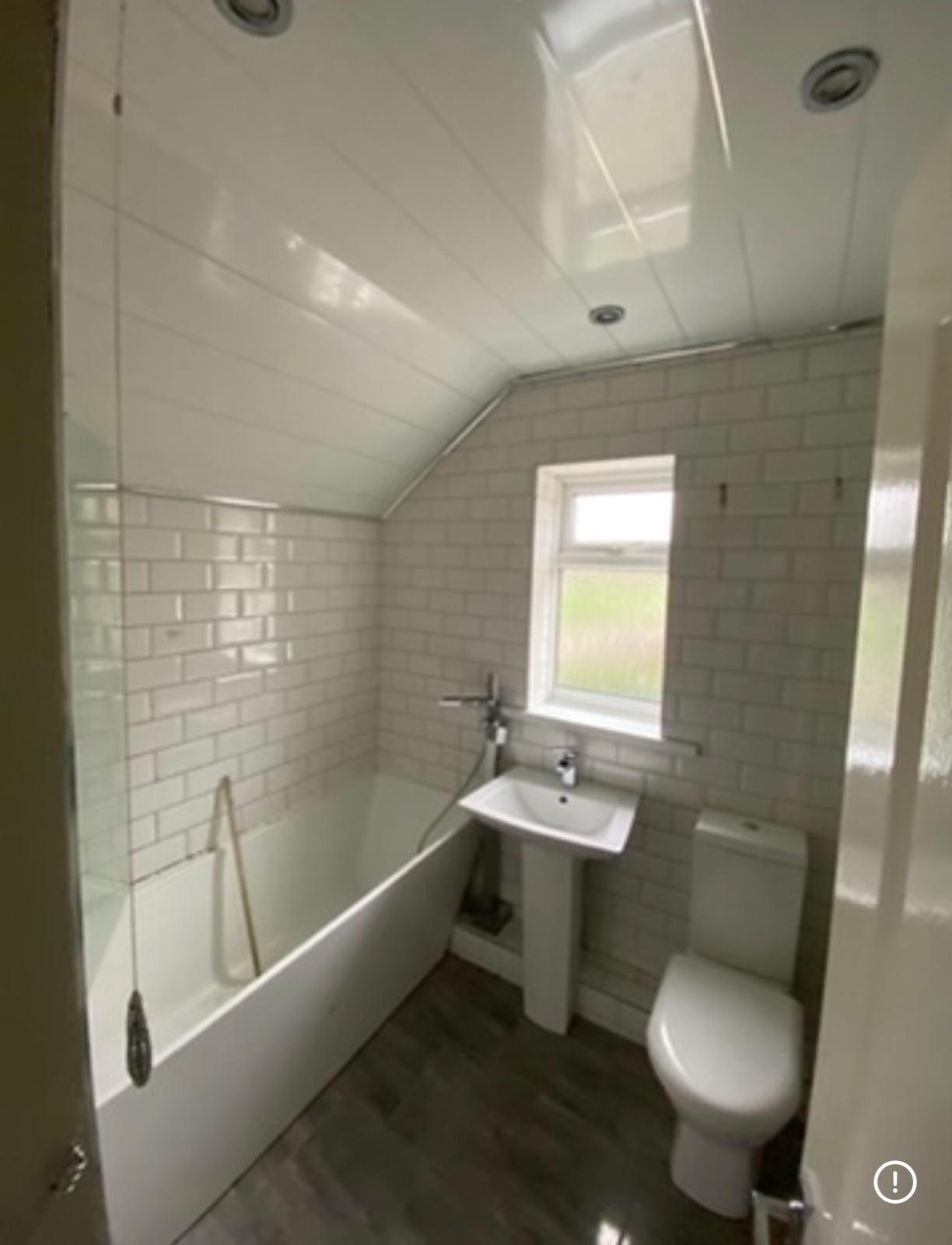 Original bathroom with white metro tiles, pedestal basin and bath under the sloped ceiling