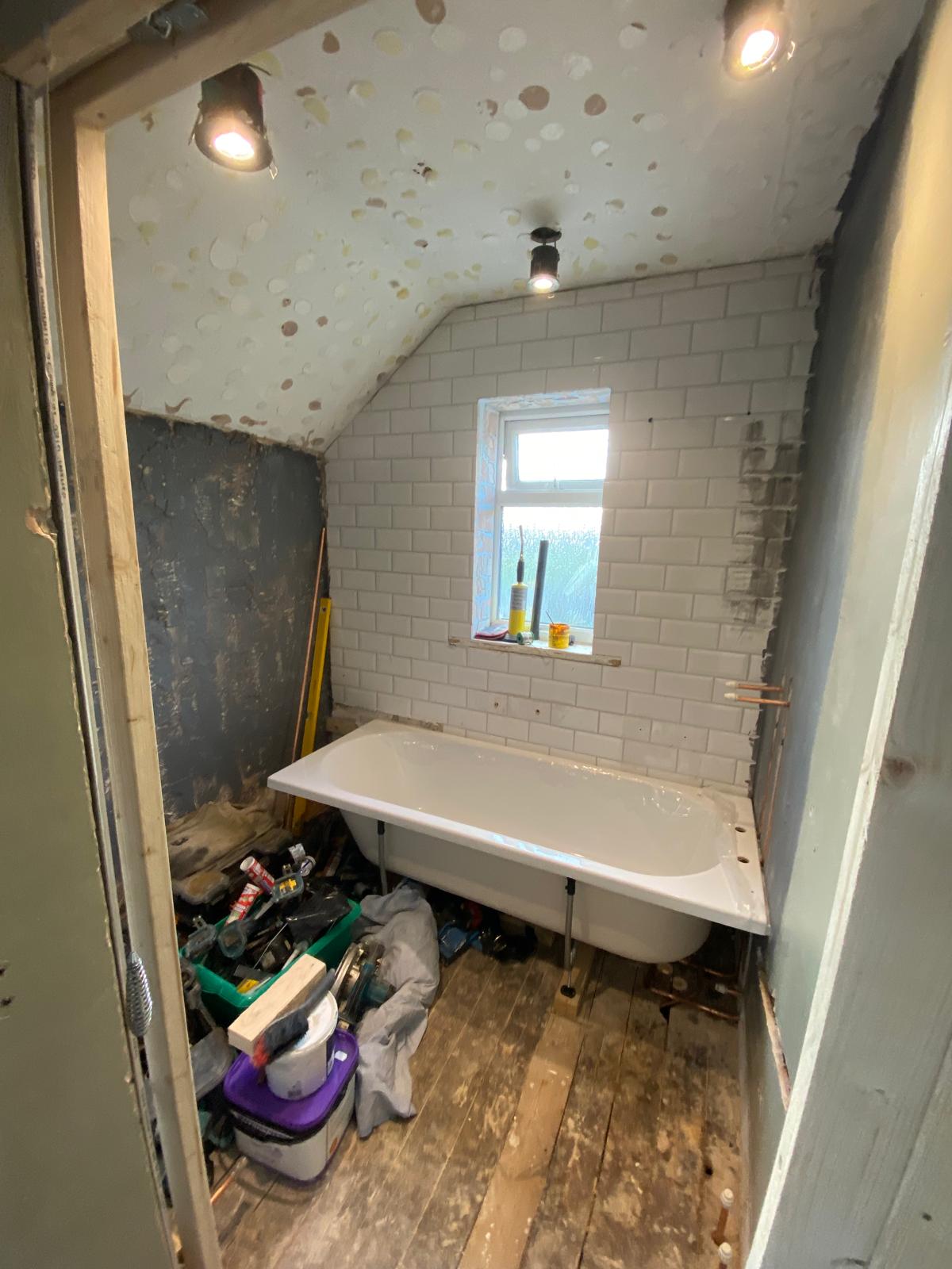 Bathroom stripped to floorboards with the bath dry fitted in its new position
