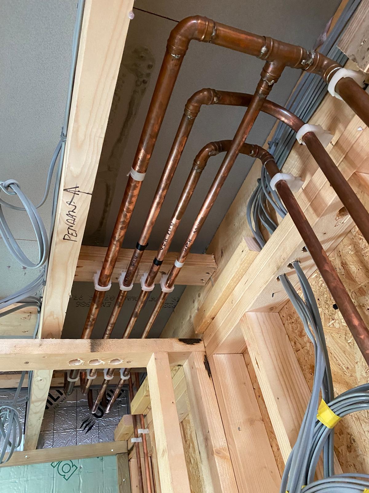 Labelled copper heating flow and return pipework clipped through ceiling joists