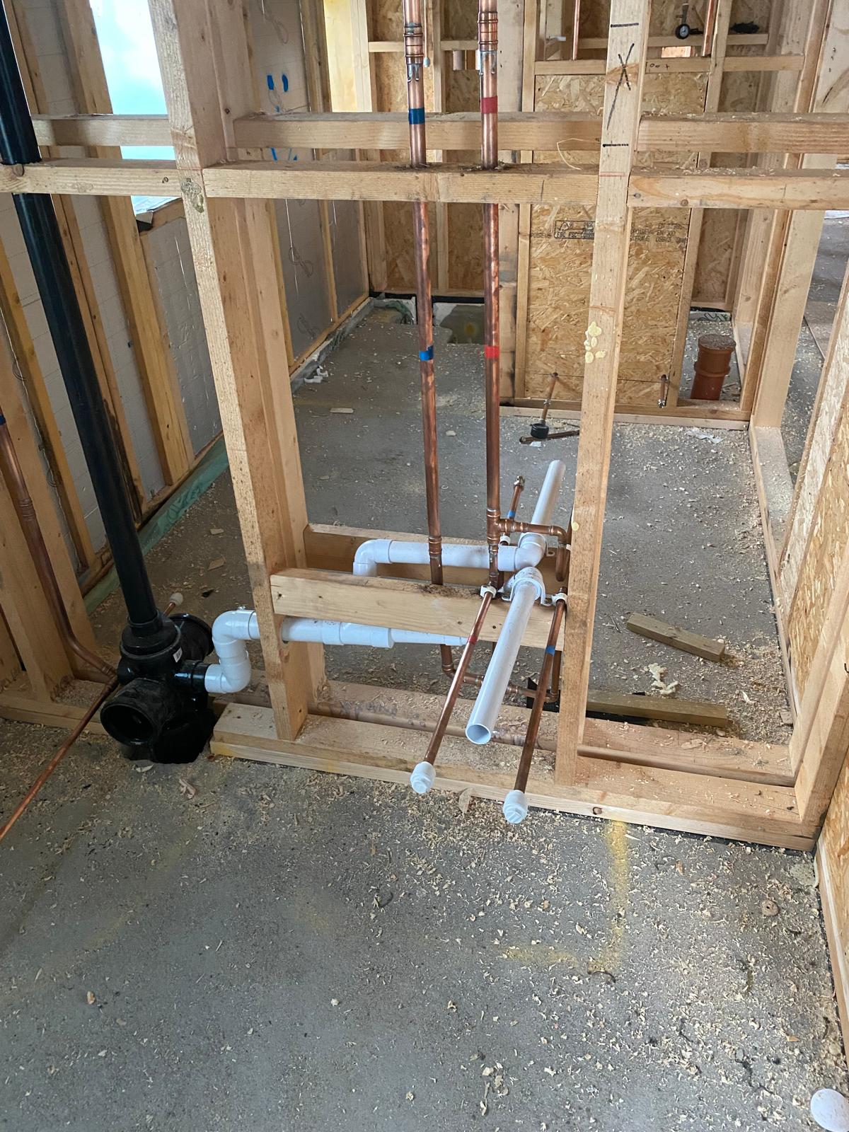 Hot, cold and waste connections framed into a shower room stud wall before boarding