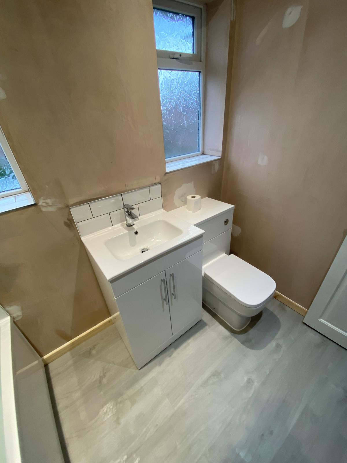 Combined vanity basin and WC unit fitted under the window on wood effect flooring