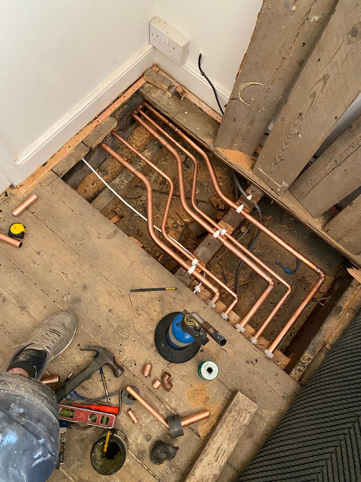 Copper heating and water runs clipped between joists in a lifted floor void