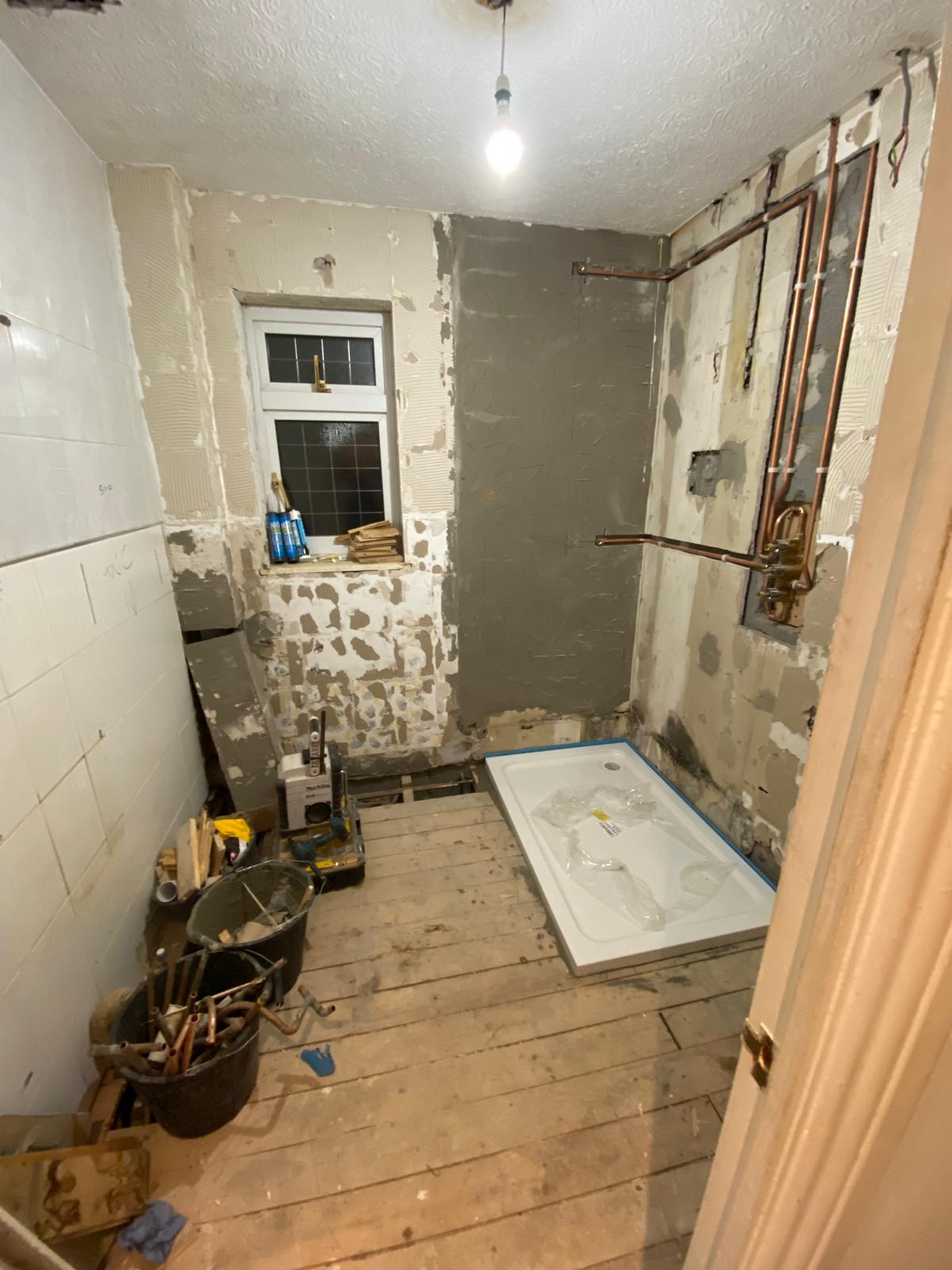 En-suite stripped back to bare walls with new shower tray and exposed copper pipework