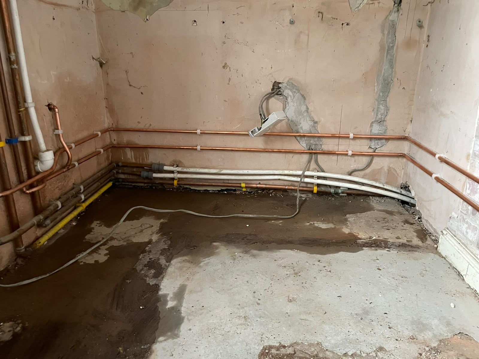 New copper pipework clipped along the brick wall with tails set out for the new kitchen layout