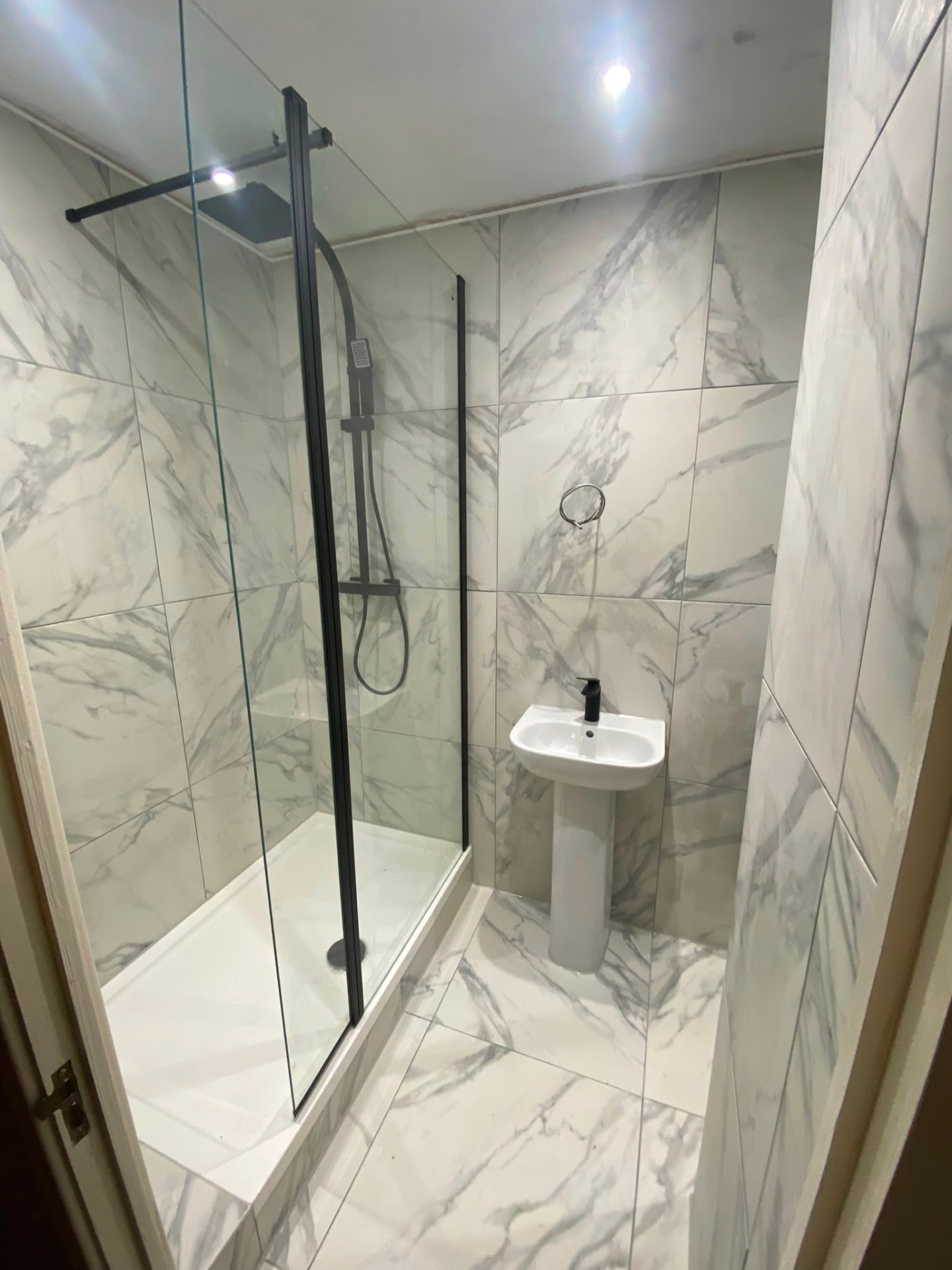 Bedlington bathroom with marble-effect tiles, black framed shower screen and black brassware