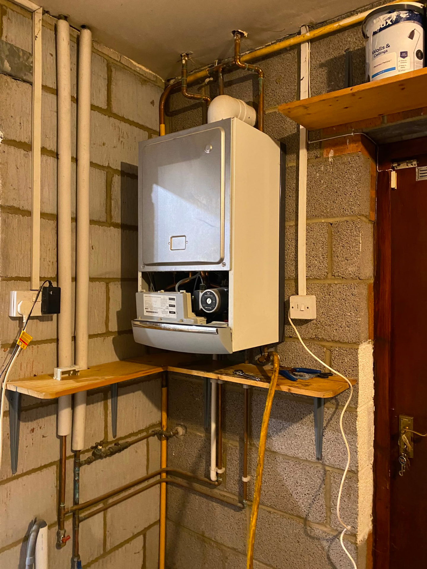 Old boiler being replaced in a Bedlington garage, with exposed pump and new copper pipework being run