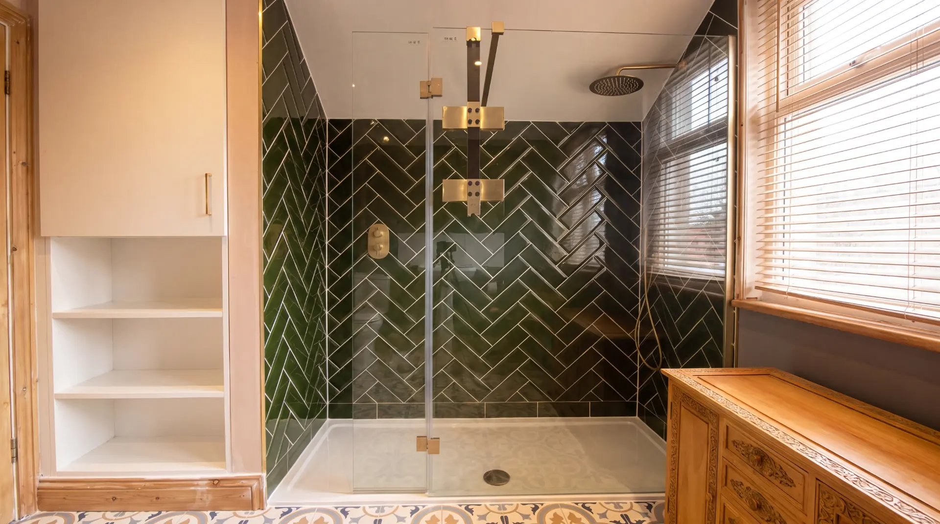 Loft shower area with dark green herringbone tiles, brass fittings and patterned floor tiles