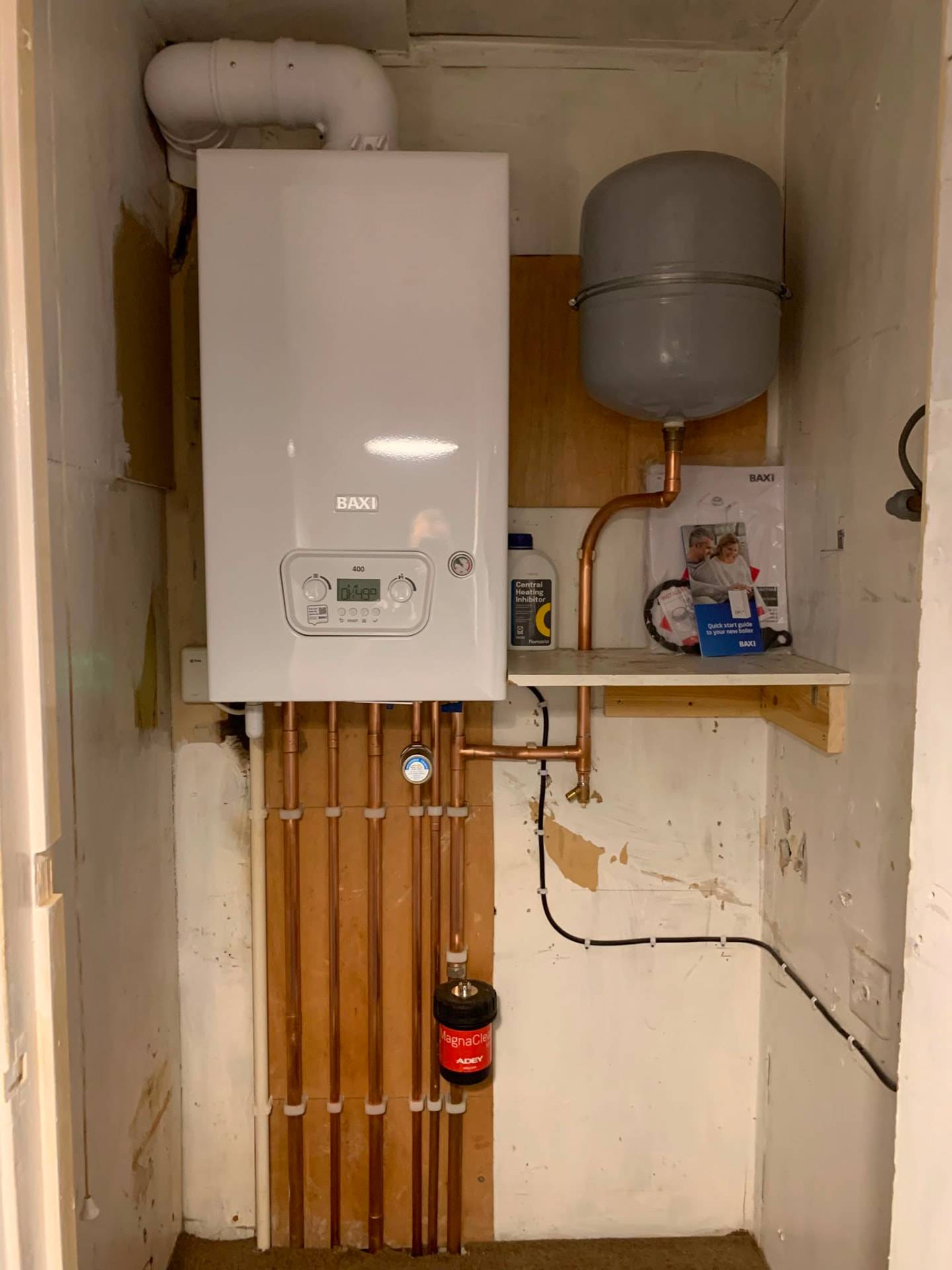 Finished boiler install with labelled valves and copper pipework clipped to the wall
